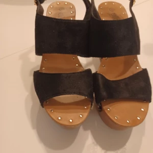 Sandaler med kilklack - Sandaler med kilklack (ca. 10 cm). Använda 2-3 gånger, inga skavanker. Köpta från Ellos. Stl. 39 Köparen står för fraktkostnader!