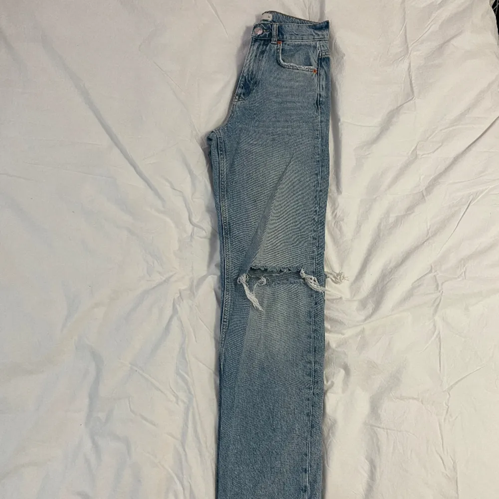 Högmidjade raka jeans med revor på knäna i modellen ”90’s high waist”, från Gina Tricot. Fint skick och snålt använda 💕   Midja: 31 cm (rakt över) Innerben: 78 cm. Jeans & Byxor.