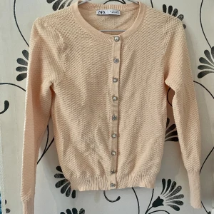Zara kofta jumper persika pärlor strass - Super snygg kofta från zara storlek S. Knappar med pärlor strass. Färg persika som är årets färg. Knappar med pärlemor/strass