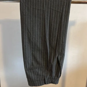 Vida randiga kostymbyxor  - Gråa randiga kostymbyxor med vida ben.  Sitter lite tight på mig så därav vill jag sälja de. 