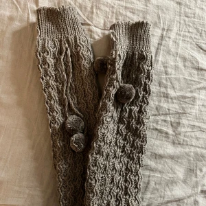 Benvärmare - Mjuka och varma benvärmare med pompoms, de är gråbruna i färg. Ganska små