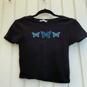 En svart t-shirt med tre blåa fjärilar framtill💗 säljer pågrund av att den aldrig kommer till användning längre!