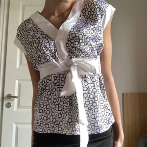 Blus - Så fin v-ringad blus med vita snören man kan knyta till en rosett längst fram eller bak. Perfekt att styla tillsammans med en mini kjol🤍🌟 Nyttskick!