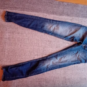 Nudiejeans blå 29/34 - Nudiejeans blå 29/34. Begagnade med en liten lagning på höger knä (se bild).