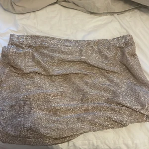 Glittrig kjol - Champangefärgad glitterkjol, man kan enkelt vika upp eller justera längden och passformen hur man vill att den ska sitta. 