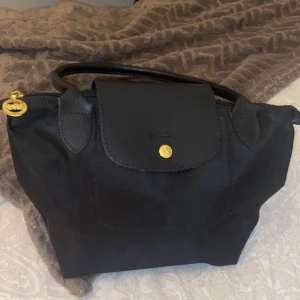 Longchamp bag - Säljer min longchamp väska då den inte används. Vet inte om den är äckta eller inte. Den har en liten ficka där man får plats med nycklar och plånbok. Superfint skick.
