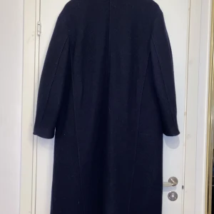 Mörkblå kappa i ull  - Ur snygg mörkblå kappa i ull från other stories i strl M, jag säljer denna då jag inte har någon användning för den längre samt att den är förstor för mig. Saknar en knapp samt sitt bälte. 