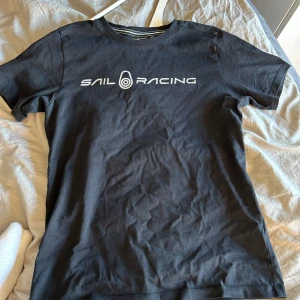 Sail racing - En svart t-shitt med märket sail racing som är jätteskön och inte har några skador. Den är i storlek 160 men passar även som en S❤️