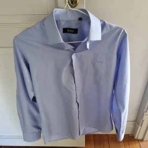 Hugo Boss Skjorta - Säljer min Hugo boss skjorta i färgen ljusblå då den är för liten flr mig. Storlek M, skicka medelande vid funderingar elr om ni vill ha fler bilder. Även öppen för byten. Priset ligger nu på 99 för den har varit uppe så länge