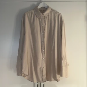 H&M Edition skjorta strl M  - Säljer en jätte fin blus från H&M Trend i strl M. Off white.  Kvalitet viskos/polyester.  Oversized modell. Beige. Snygg knyt detalj vid ärmarna.  Använd 2ggr.  Nypris 499:-