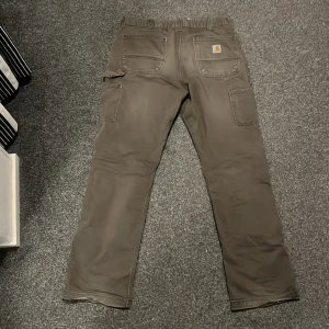 Carhartt Carpenter Byxor - Vintage Carhartt carpenter byxor i storlek 34x34. Använda men i gott skick utöver lite slitage längst ner. Pris kan diskuteras!