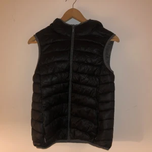 Svart väst dunjacka - Bra skick Med luva och två fickor med dragkedja  Specifika mått kan ges på förfrågning