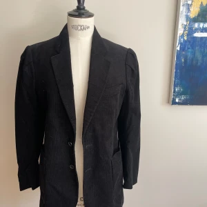 Svart Hopekostym i stl 38 - Din Hopekostym i svart, smalrandig Manchester. Stl 38 i både byxa och kavla. Kavajen har en liten puffärm.