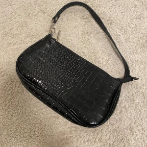 mini axelväska i skinn  - Mini axelväska i skin.  perfekt skick då väskan knappast är använd. Man kan ta bort bandet på väskan 