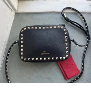 Valentino väska  - (Intressekoll) Super snygg valentino camera bag❤️ Självklart äkta!! Första bilden lånad. Enda defekten är att de har gått bort lite av färgen där det står ”valentino” och den är sliten men tror de nog går att fixa❤️ därav priset, en nit på bandet borta