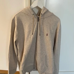 Ralph Lauren zip hoodie L - Fin Ralph Lauren zip i storlek L, använd några få gånger men är fortfarande i toppskick. Nypris ligger på ca 2000kr. Säljs för 800kr men priset kan diskuteras. Kan frakta samt mötas upp. 