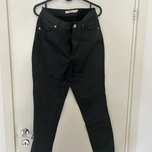 Jeans 38 - Jeans i läderimitation i bra skick. Mycket smickrande. 