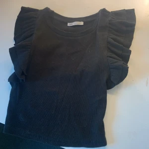 💝Svart topp med volanger💝 - Säljer denna trendiga tröja med volanger på armarna. Storlek S/XS passar mig som brukar vara xs med står på att det är S.💝köp nu