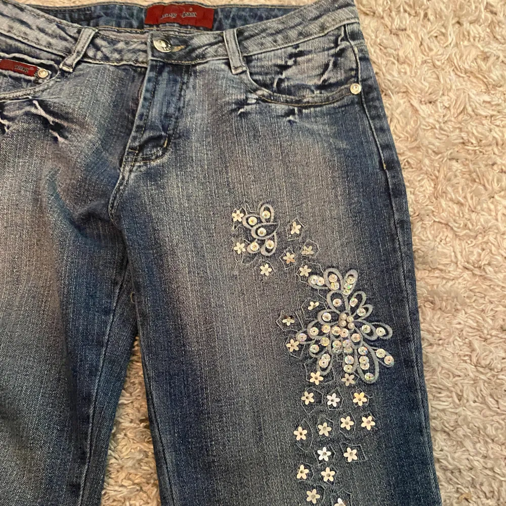 Utsvängda lowwaist jeans. De har jätte coolt blom mönster i paljetter på höger ben. De har även andra coola detaljer på fickorna och bakbenen och en snygg tvätt. Det ända felet är att dragkedjan är trasig, men det syns inte när man har på sig dem❤️. Jeans & Byxor.