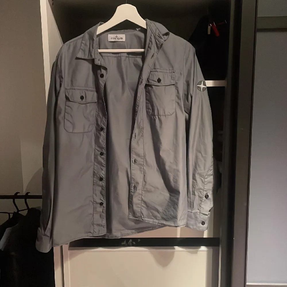 Grå Stone Island Junior Overshirt/Skjorta. Storlek 164/170. Plagget är i använt fint skick. Ny pris 2300. Mitt pris 950. Skjortor.