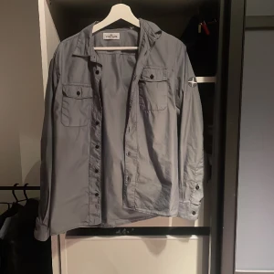 Stone Island Junior Overshirt/Skjorta - Grå Stone Island Junior Overshirt/Skjorta. Storlek 164/170. Plagget är i använt fint skick. Ny pris 2300. Mitt pris 950