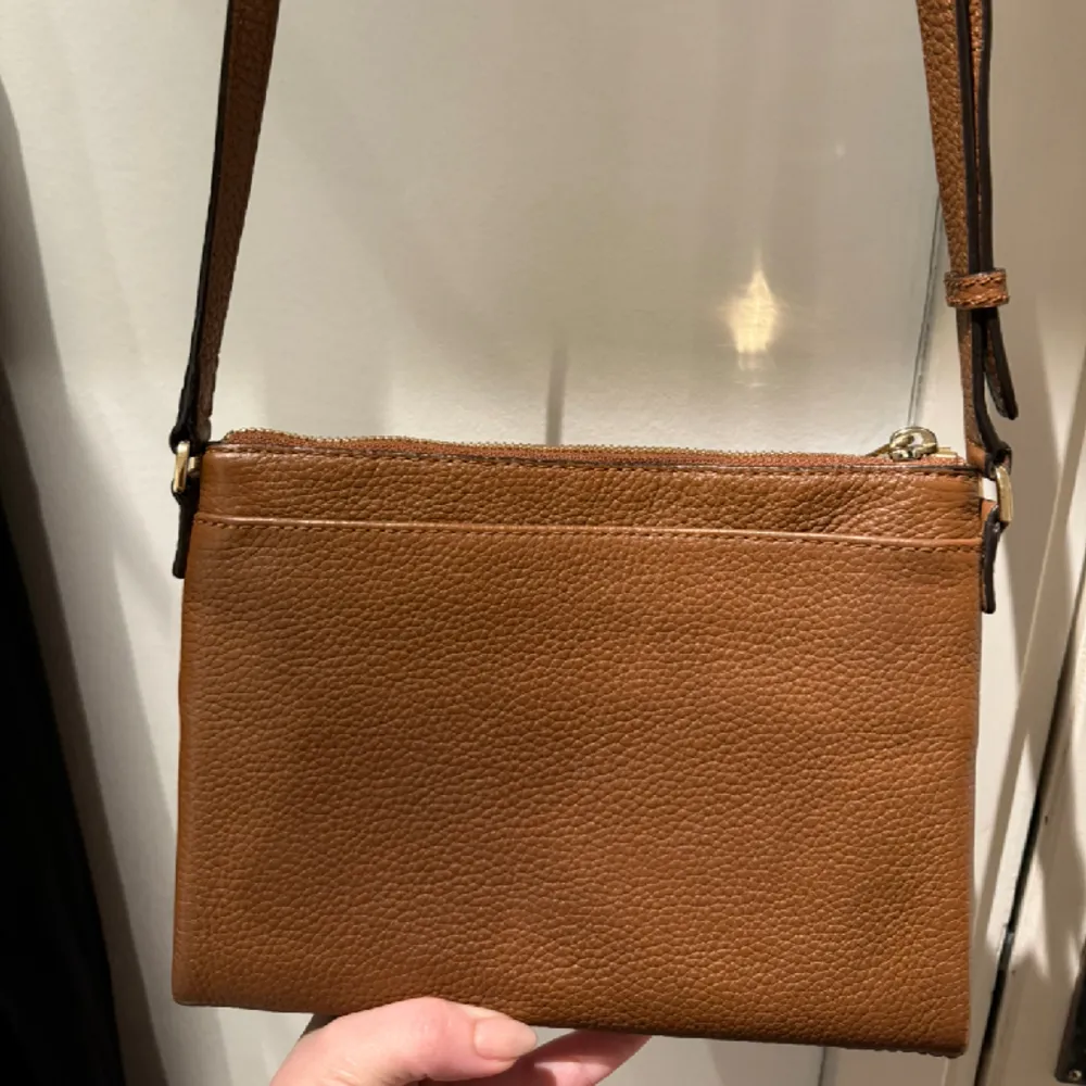 Brun Michael Kors crosdbody väska med double zip och kortförvaring i mitten. Använd fåtal gånger och inga fläckar inuti. Material är “pebbled leather”. Skriv för fler bilder, har bild på authenticity tag också. Säljer för 750kr eller bud.. Accessoarer.