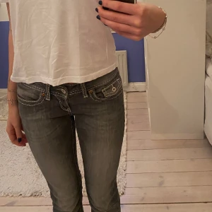Lågmidjade jeans - Grå lågmidjade jeans med vit söm som ger de en unik design. Köpta second hand 💞Först till kvarn gäller! 