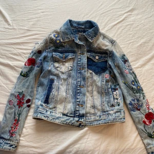 Unik jeansjacka  - Super fin, unik jeansjacka, fylld av broderade blommor. Ägt den länge men använt sparsamt. Den har inga synliga slitage förutom distress som är gjorda av tillvärkaren.   Du står för frakt😊