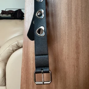 Svart skärp  - Ett svart skärp med solverhjärtan runt hålen.