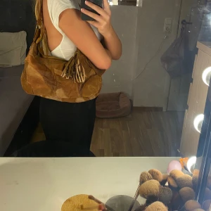 Väska - Brun jätte fin väska. Vet inte vart den är ifrån då jag fått den i present för några månader sedan. (Går att ta av tofsarna om man vill.)