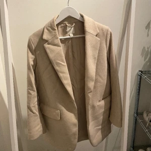 Beig  - Lite tjockare kavaj som går att ha som jacka. 