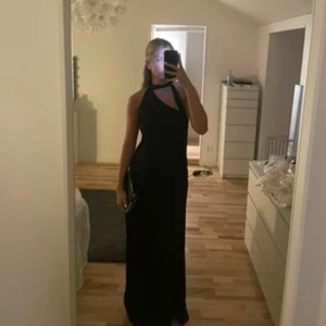 Balklänning - Säljer min svarta balklänning med en ”scarf” detalj vid halsen och slits. Det är storlek 38 men har sytt in den hos en skräddare då den var lite för stor för mig. Märket är about you RÆRE by Lorena Rae.💗