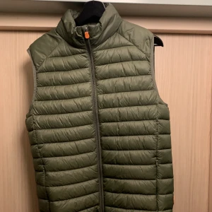 Save the duck väst  - En lätt dunväst från Save the duck. Storlek L, men passar för de som normalt ha M. Jag är 180 cm och väger ca 77kg och den sitter bra på mig. Knappt använd så den är i bra skick!