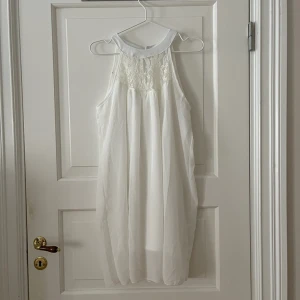 Vit klänning i chiffong  - Vit klänning i chiffong. Spets upptill fram och bak. Insydd underklänning. Liten fläck på insidan (se bild) men syns inte igenom på baksidan. Storlek L. Aldrig använd. Bara att fråga om det är något du undrar! 