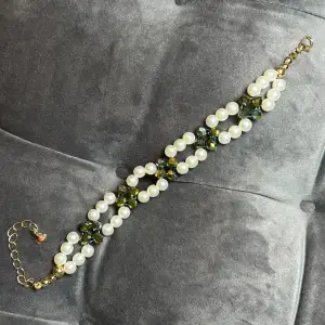 Handgjort pärlarmband med vita runda pärlor, grå/gröna hollografisks fasetterade pärlor och guldigt spänne. Justerbar passform mellan 19-24 cm.