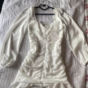 Klänning - Jättefin vit klänning med volang nedtill och ballongärmar. Köpt från Bubbelroom, oanvänd🤍🤍