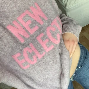 Lila stickad tröja från hm - Stickat tröja från hm,   ”New electic” Köpt second hand, i bra skick Hon på bilden är 166 cm och storlek xs/s