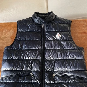 Moncler Gui väst - Västen är storlek 4/L. Cond 9/10, väldigt bra skick. 1,300 , kom privat för mer info! Pris kan diskuteras. Billigt pris då jag ej vet om den är äkta eller ej