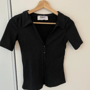 Svart topp - Svart topp med bara tre knappar. Toppen är öppen så att magen visas💘