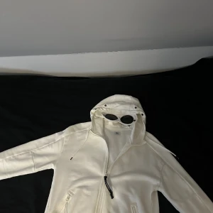 CP Company Goggle Hoodie Vit - Mycket sparsamt använd, 9/10 skick, inga flaws eller likande. Nypris ligger på 3150kr, tags och qr-kod för bevis att den är äkta finns!  Hör gärna av er vid frågor. Mvh// Lucas