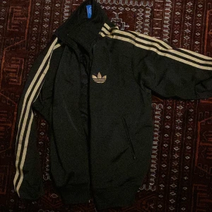 Adidas tröja  - Zip up adidas med guld ränder. passar s/m