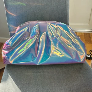 Necessär - Drömmig clutch/necessär i holographiskt material som skimrar✨️Från Nelly. Mycket plats i för tex smink eller annat.