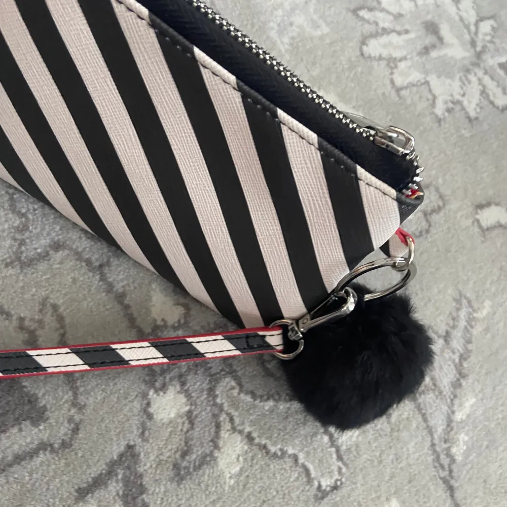 Plånbok med zebra mönster röd i insidan med en svart fluffboll som hänger på utsidan som dekoration . Accessoarer.