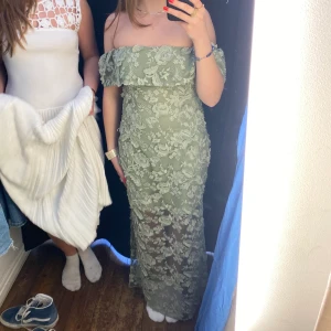 Grön långklänning - En grön klänning med spets av större blommor. Den är från Twist & Tango och har ett orginalpris på 1499kr. Varan är aldrig använd, alltså i nyskick.