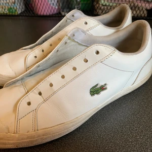 Lacoste sneakers  - Vita klassiska Lacoste sneakers stl 42 i bra skick. (7/10) Nytvättade skosnören följer naturligtvis med 😀