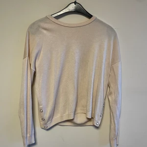 Tröja  - Beige tunnare tröja med knappar i sidan. 