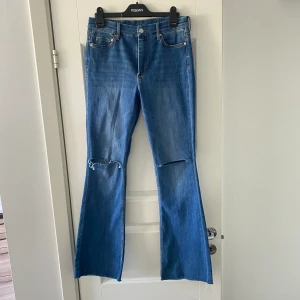 Jeans - Blå bootcut jeans från H&M med hål i knäna. Storlek 40, bra skick.
