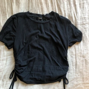 Svart t-shirt  - Svart t-shirt, med dragsko på sidorna