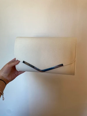 Väska - Superfin kuvertväska som passar perfekt till balen eller festligare tillfällen, aldrig använd😊Den är vit med lite glitter i, följer även med en kedja så man kan använda den som en axelväska oxå🫶🏻