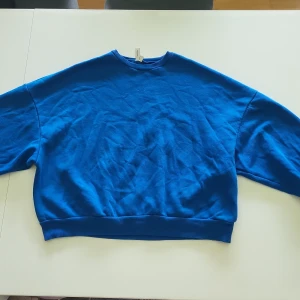Blå sweatshirt - En supermysig blå sweatshirt med långa ärmar och ribbstickade muddar vid ärmslut och nederkant. Cool blå färg! Säljer då jag inte använder den längre. Bra skick. (Pris kan diskuteras)